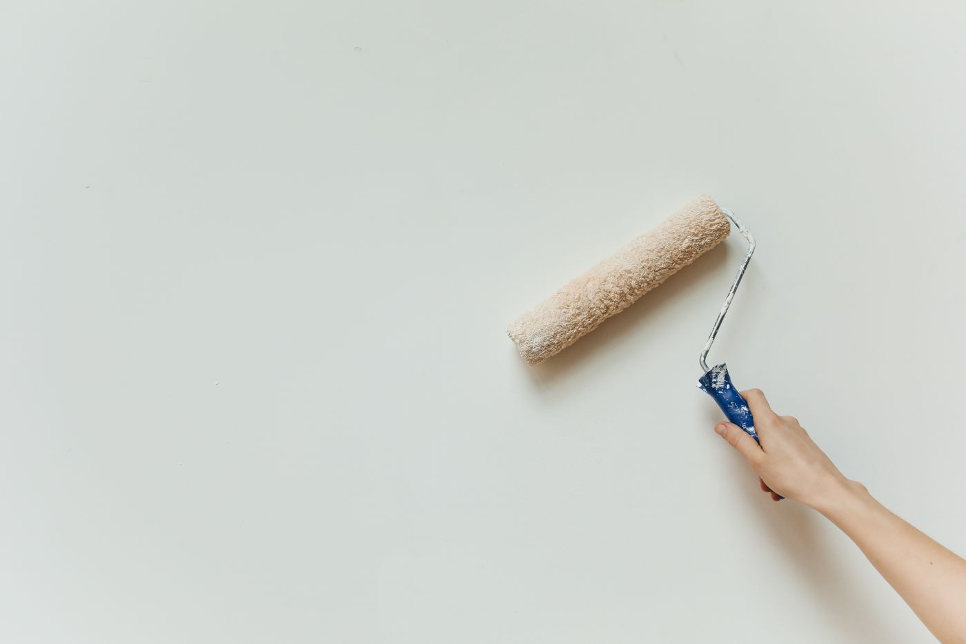 Paint roller repainting a wall in a finished rental suite between tenants